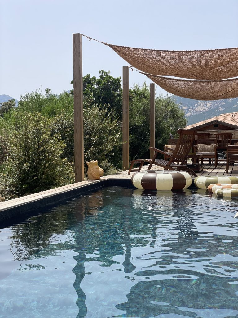Piscine de La Villa Geneviève avec sa terrasse ombragée, bouée rétro et environnement naturel au pied des montagnes corses près de Calvi.
