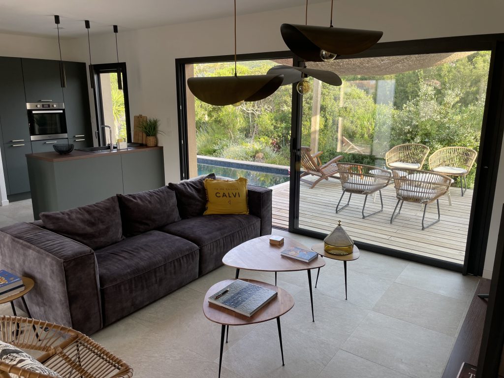 Salon de La Villa Geneviève avec une large ouverture sur l'extérieur, créant une connexion fluide entre l'intérieur et la nature environnante, offrant une sensation de vivre en harmonie avec l'environnement.