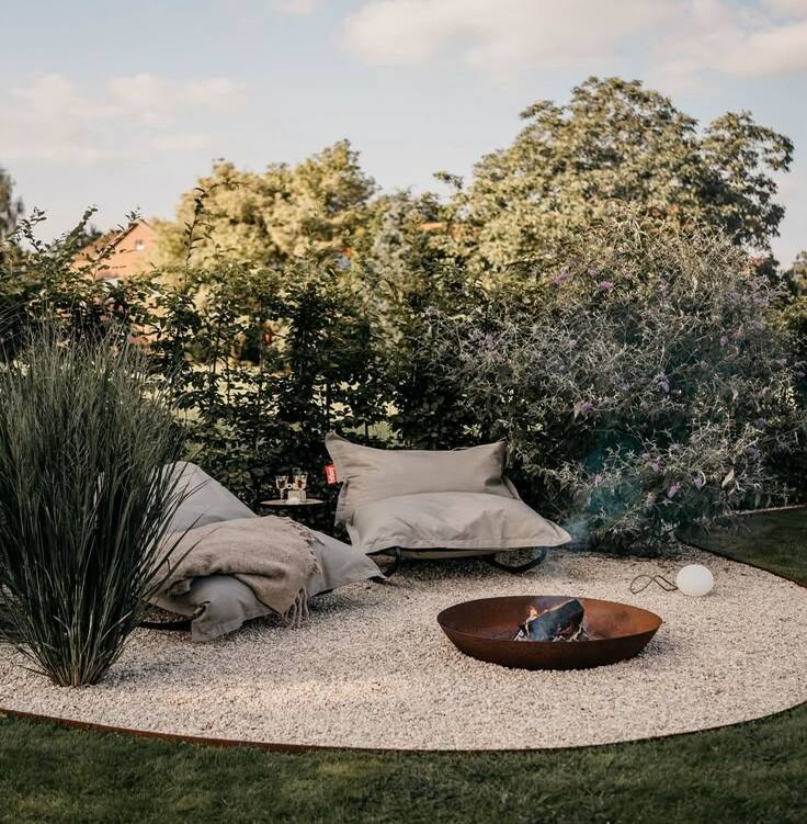 Petit salon cosy dans un jardin intimiste de style méditerranéen avec un brasero central qui ajoute une touche chaleureuse à l'atmosphère sereine.