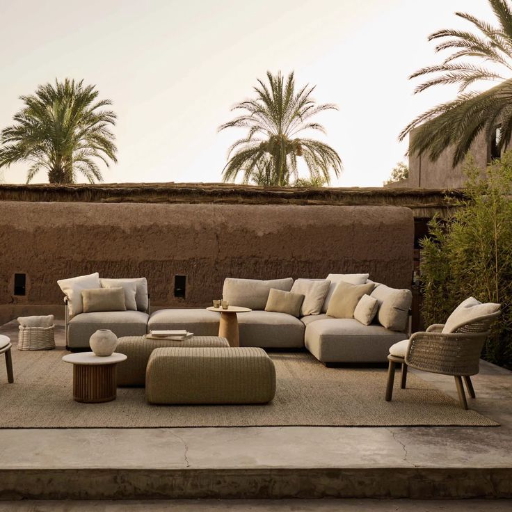 Salon d'extérieur méditerranéen très confortable dans des tons neutres, offrant une atmosphère chaleureuse au crépuscule, idéal pour des moments de détente en plein air