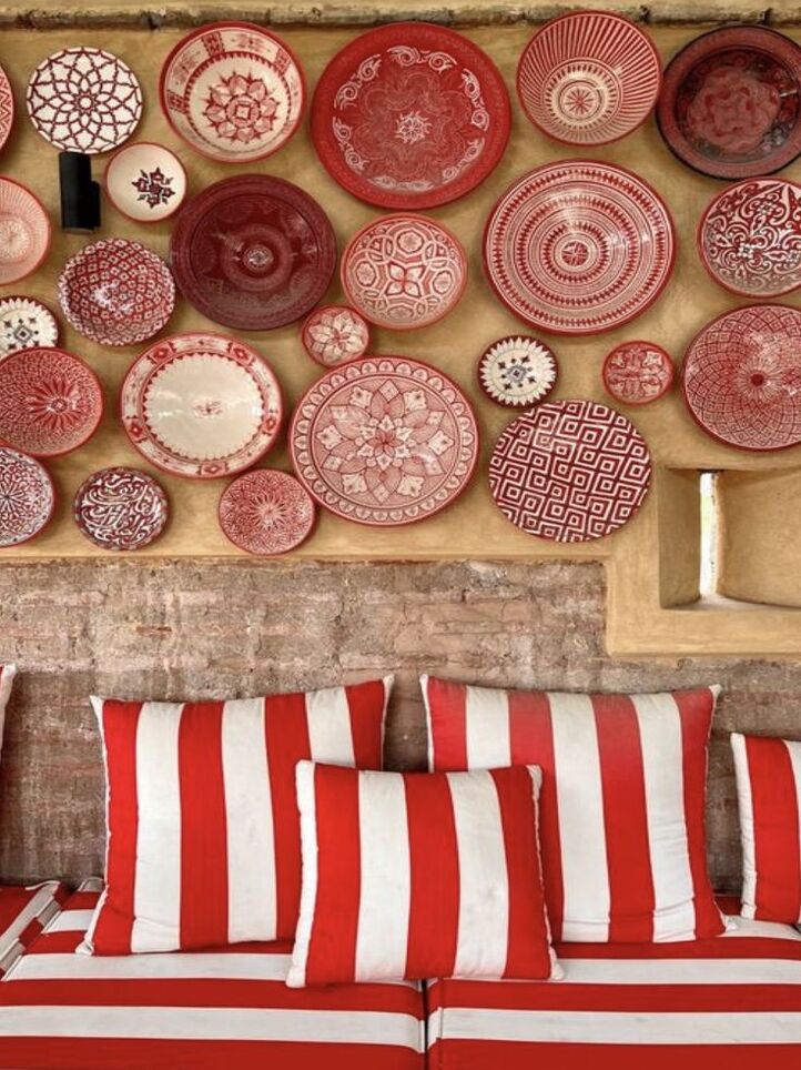 Contraste de style entre des poteries de style portugaise accroché au mur et des banquettes rayées à bande blanche et rouge