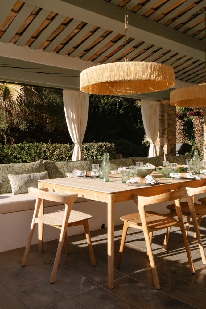 Table en bois clair et suspension en raphia, élégance naturelle.