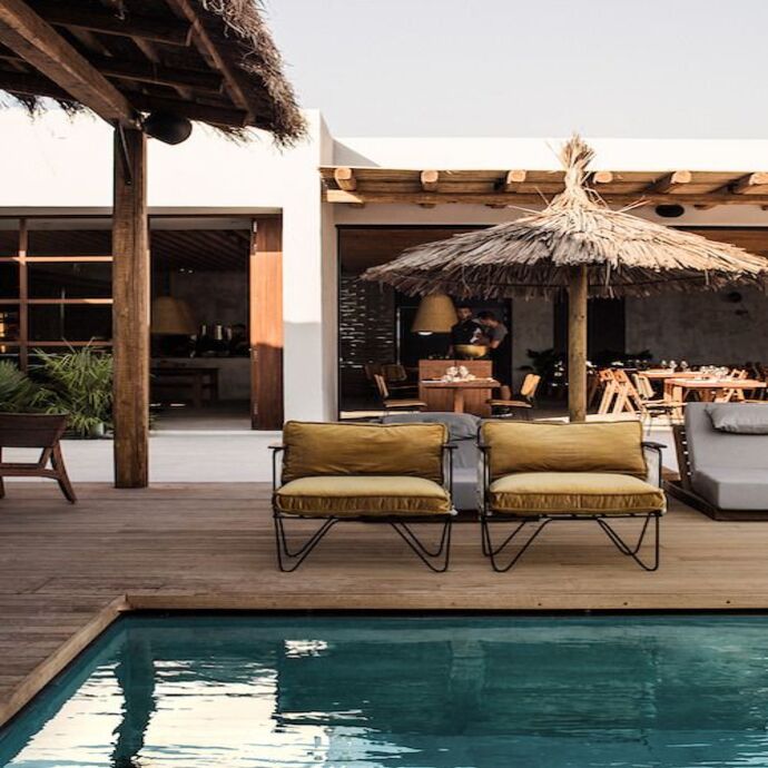 Petit salon convivial face à la piscine abrité sous des toitures en cannage et rotin. Une esthétique méditerranéenne authentique entre légèreté et élégance naturelle